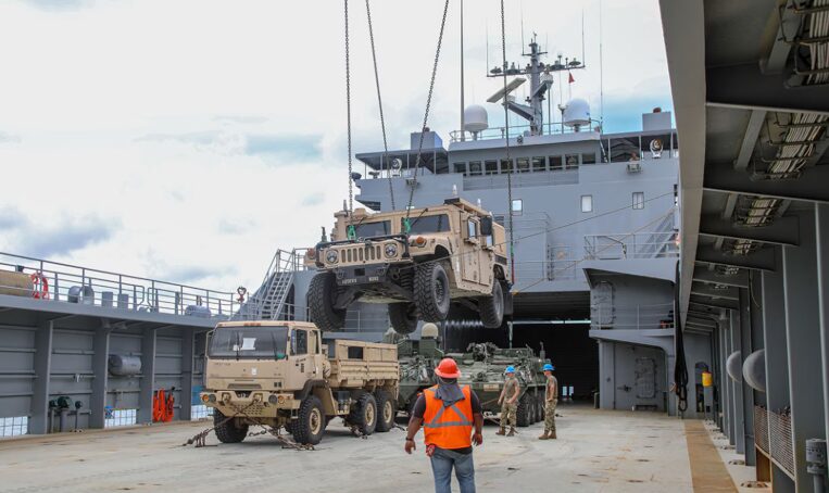 Military vehicles being loaded aboard a logistics vessel